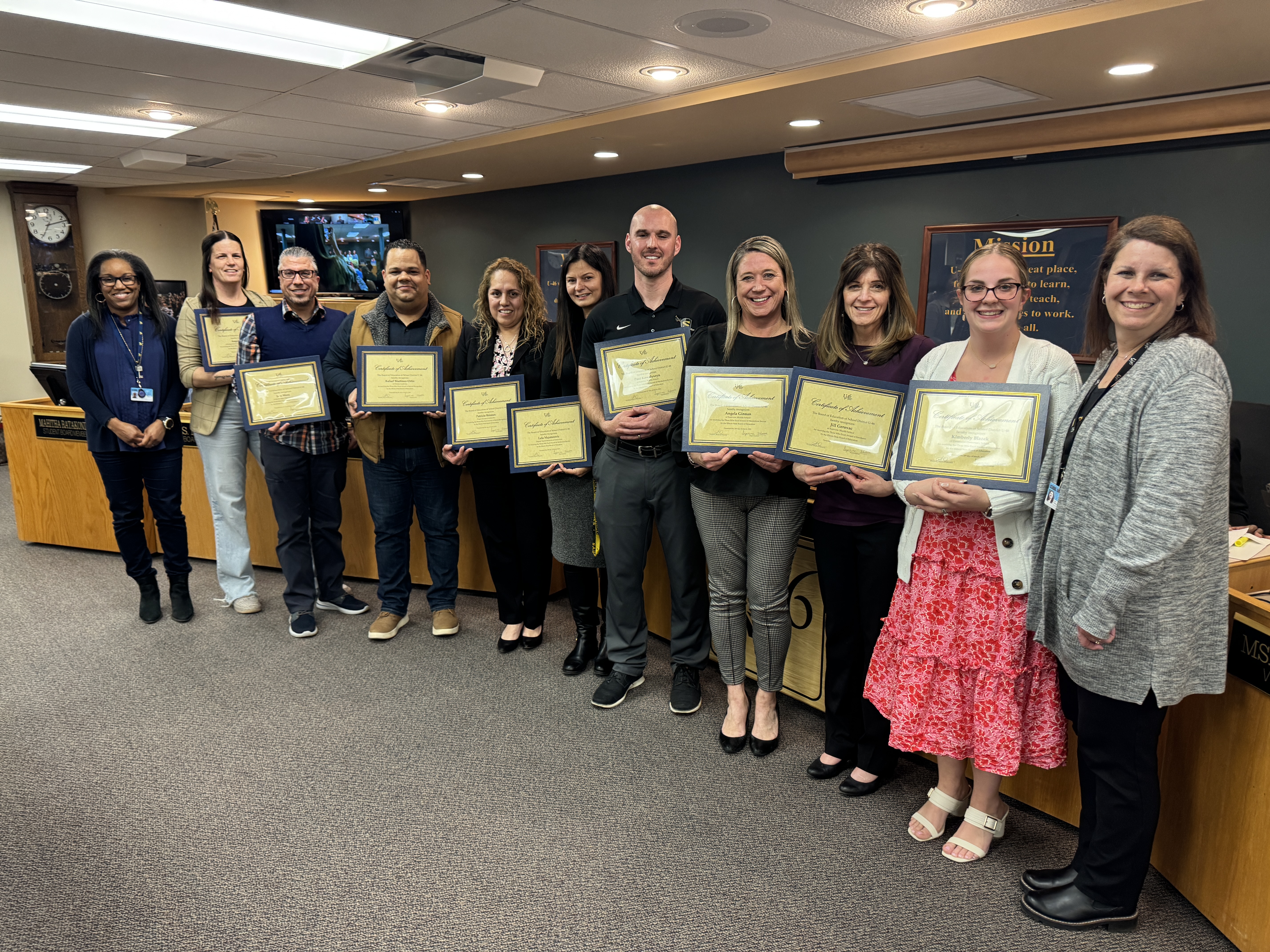 eleven people stand as they are recognized with an award